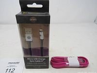 Front view of boxed Harley-Davidson micro USB cable beside coiled pink cable