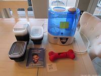Group shot of humidifier, stacked plastic containers, red dog bone toy, Think Like a Monk DVD