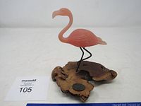 Full view of pink flamingo sculpture on driftwood base with scale reference