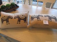 Both elephant pillows on table