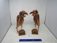 Front view of both copper parrot statues with ruler for scale