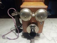 Front view showing oak case, twin bells, mouthpiece, receiver and cord