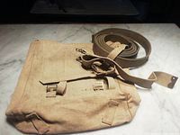 Front view of khaki canvas satchel with rolled double webbing belt and L strap
