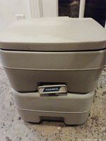 Front view of Camco portable toilet with lid closed