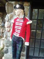 Full view of mannequin wearing red doublet, tartan trews, black Glengarry cap