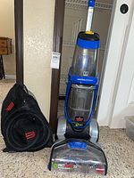 Full view of carpet cleaner with mesh bag of accessories
