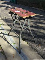 Overall view of folded workbench on pavement showing top surface and steel legs
