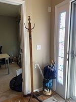 Full view of wood coat rack and umbrella stand with umbrellas