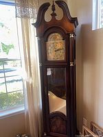 Full view of grandfather clock showing case, arched bonnet, glass door