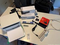 Top view showing printer, toner box, paper stack, power strips, extension cord, pens, cables, boxed accessory