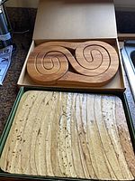 Box containing two-piece carved swirl board above ridged board