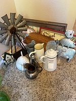 Lot overview showing windmill, pitchers, urn, teapot, bookends, jars, trays and framed pieces