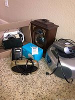 Group shot showing boombox, mantel clock, Echo Dot box, gold alarm clock, surge protector, cables