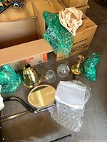 Group view showing brass lamp base, two unwrapped glass globes, oval mirror, bubble-wrapped items