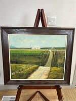 Full view of framed painting on easel