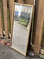 Full view of mirror leaning against fence