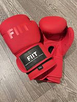 Pair of red FIIT boxing gloves on floor