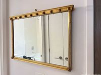 Front view of rectangular gilt framed mirror mounted on wall