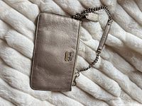 Front view of Coach pewter wristlet on white background