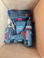 Drill, battery, charger and closed bit case inside shipping box