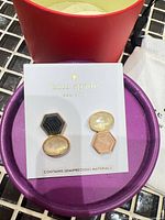 Earrings on card inside open gift box on tiled surface