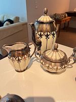 Teapot, creamer, covered sugar in silver overlay