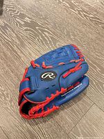 Front palm side of blue Rawlings glove showing logo and red lacing