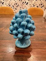 Front view of blue ceramic pine cone on table