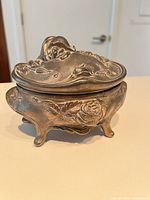 Front view of ornate silver-tone trinket box with lid closed