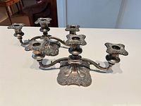 Both matching silver three-arm candelabras side by side