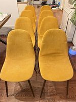 Front view of all eight yellow fabric dining chairs aligned