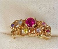 Front view of 14k gold ring showing central pink stone and six surrounding coloured stones