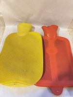 Yellow and red rubber hot water bottles side by side