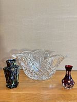 All three items side by side: crystal bowl centre, multicolour art glass vase left, cranberry cut-to-clear vase right