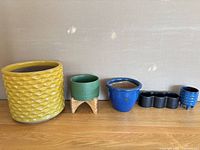Group of five ceramic plant pots lined up on wood floor