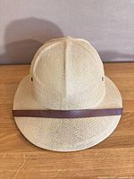 Front view of tan woven pith helmet with brown band