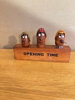 Front view of teak block holder with three bar tools showing faces and “OPENING TIME” text