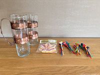 Full lot: two copper-band glasses, unopened coaster pack, bundles of plastic cocktail picks