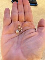 Single pearl screw-back earring on hand