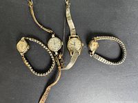 Four vintage ladies wristwatches laid out on black background