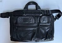Full front view of black leather Tumi messenger bag with strap attached