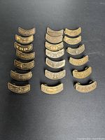 Full lot of 18 bronze curved bar pins displayed in two columns