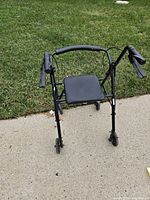 Front view of black 4-wheel rollator walker showing seat and handles