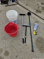 All six items laid out: white bucket, red bucket, two squeegees, brush, spray bottle