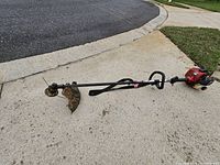 Full view of string trimmer showing straight shaft, head, engine