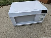 Front and top view of white GE countertop microwave showing control panel, door, viewing window and overall condition