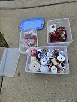Clear tote with numerous ribbon spools; separate bins with wrapped cardinal figurines