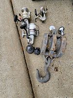 Group shot of three reels, two compasses, large snatch block, small pulley, hitch ball on concrete