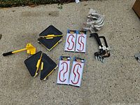 All items laid out on pavement showing dollies, lifter, packaged red S hooks, silver hooks, black hooks