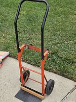 Front view of steel P-handle hand truck showing frame, wheels, toe plate with wood strip